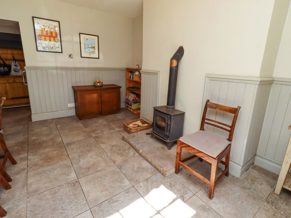 A living room with a stove and a chair at Gamekeepers Cottage in Chillingham near Chatton