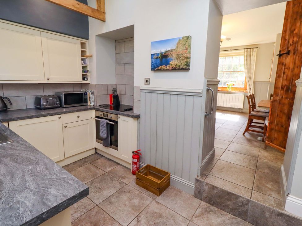 A kitchen with appliances and a dining area at Gamekeepers Cottage in Chillingham near Chatton