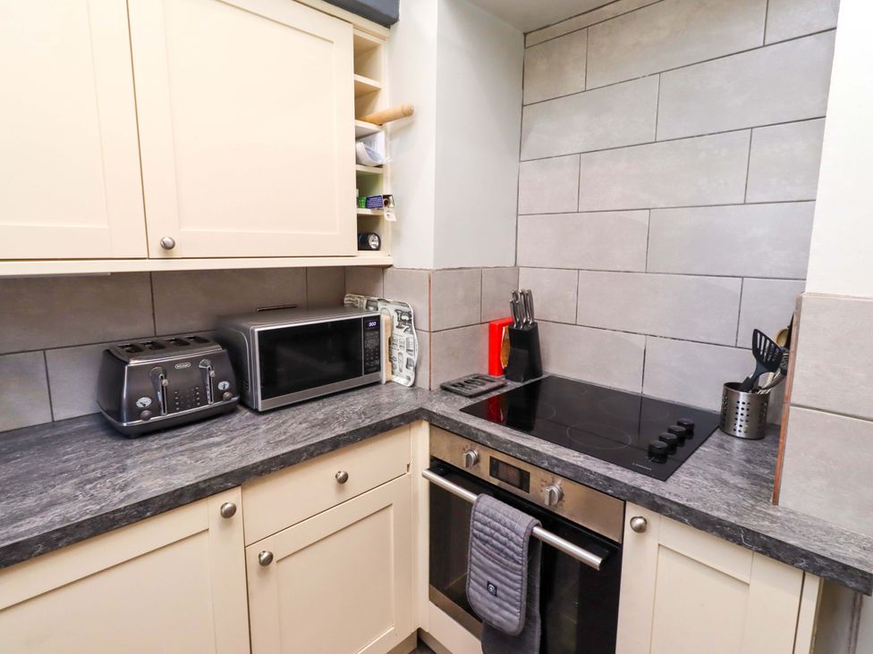 A kitchen with a microwave, toaster, and induction cooktop at Gamekeepers Cottage in Chillingham near Chatton