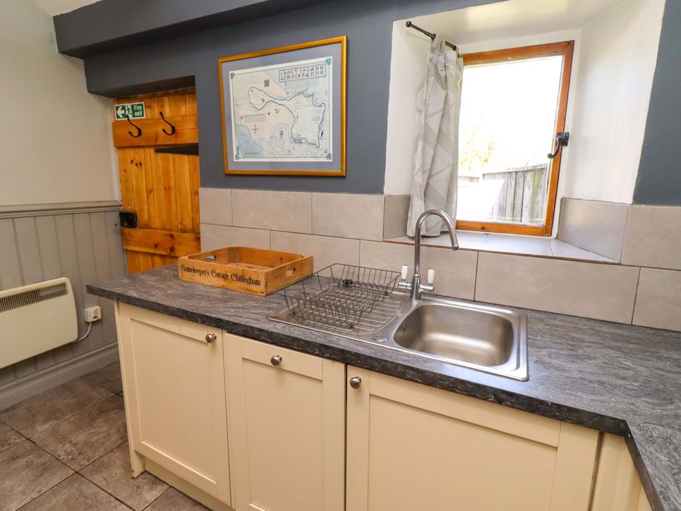 A kitchen with a sink and dish drying rack at Gamekeepers Cottage in Chillingham near Chatton