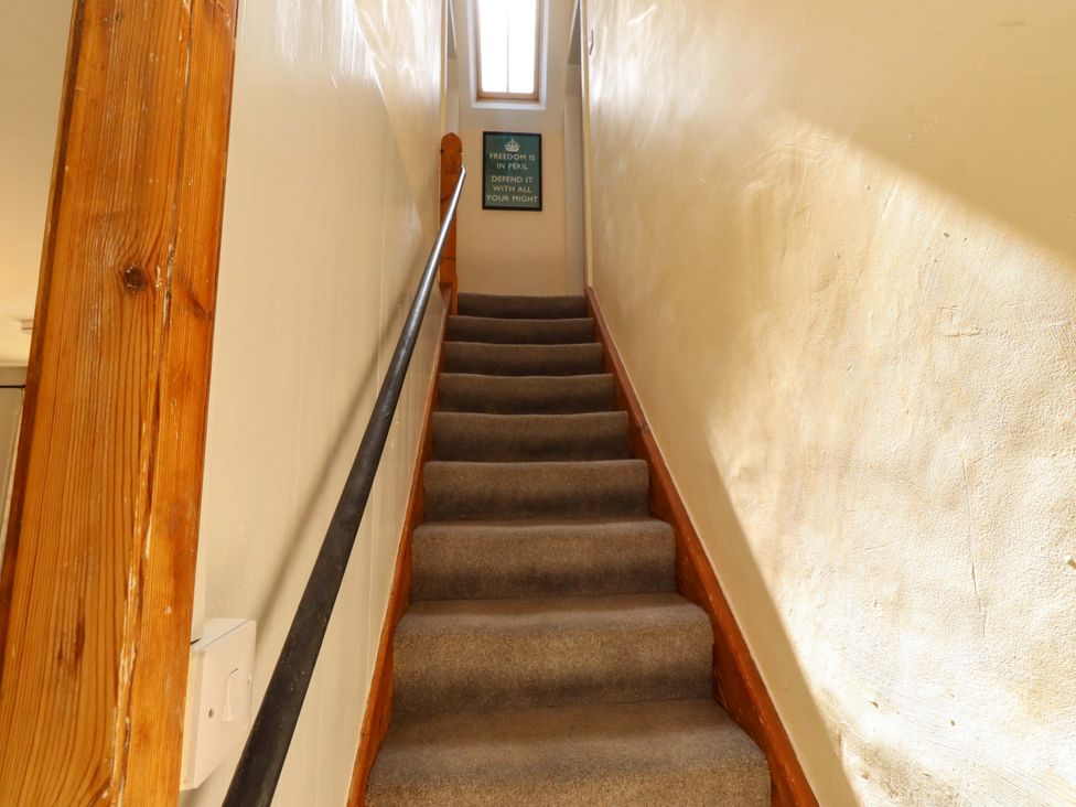 A staircase with carpet and handrail at Gamekeepers Cottage in Chillingham near Chatton