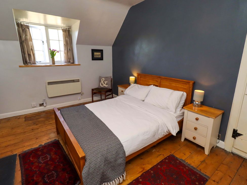 A bedroom with a bed and bedside tables at Gamekeepers Cottage in Chillingham near Chatton