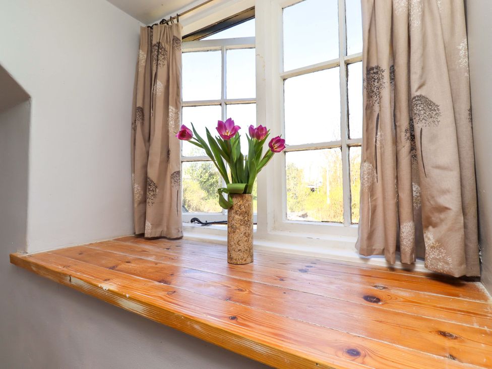 A window nook with a shelf and flowers in a vase at Gamekeepers Cottage Chillingham near Chatton
