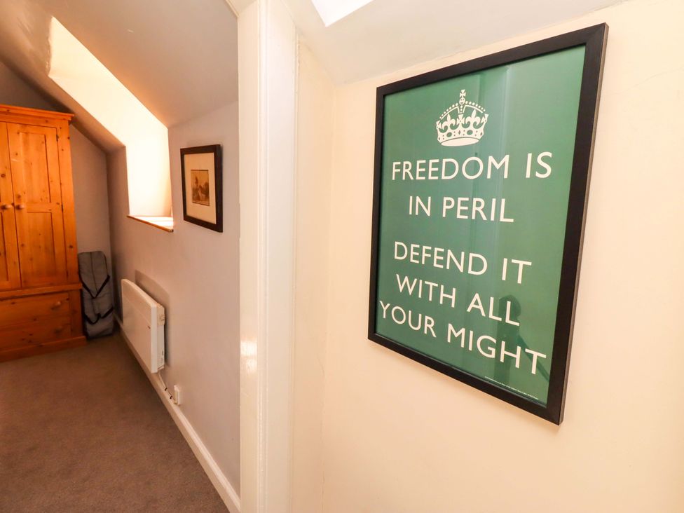 A hallway with a wardrobe, radiator, and wall art at Gamekeepers Cottage in Chillingham near Chatton