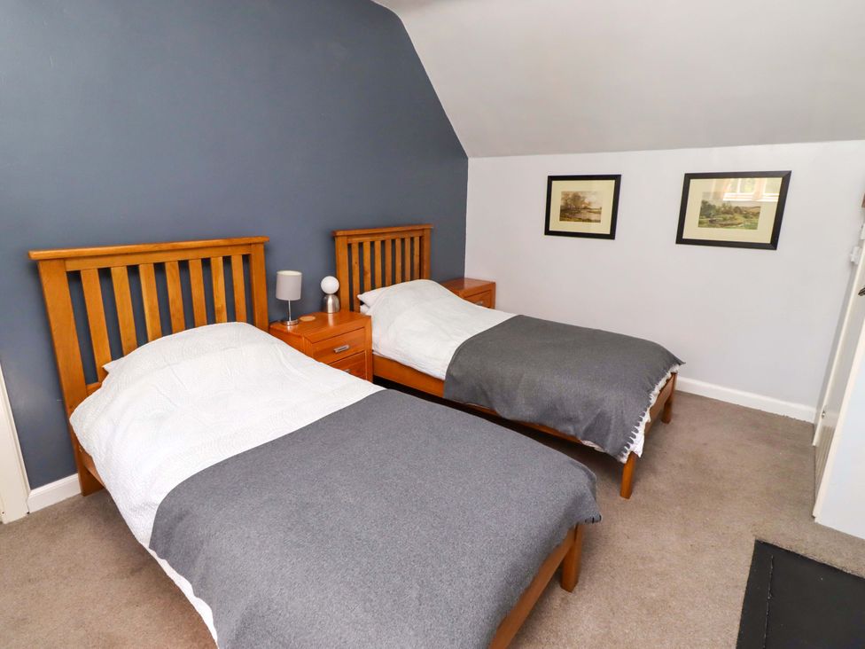 A bedroom with two beds and a nightstand at Gamekeepers Cottage Chillingham near Chatton