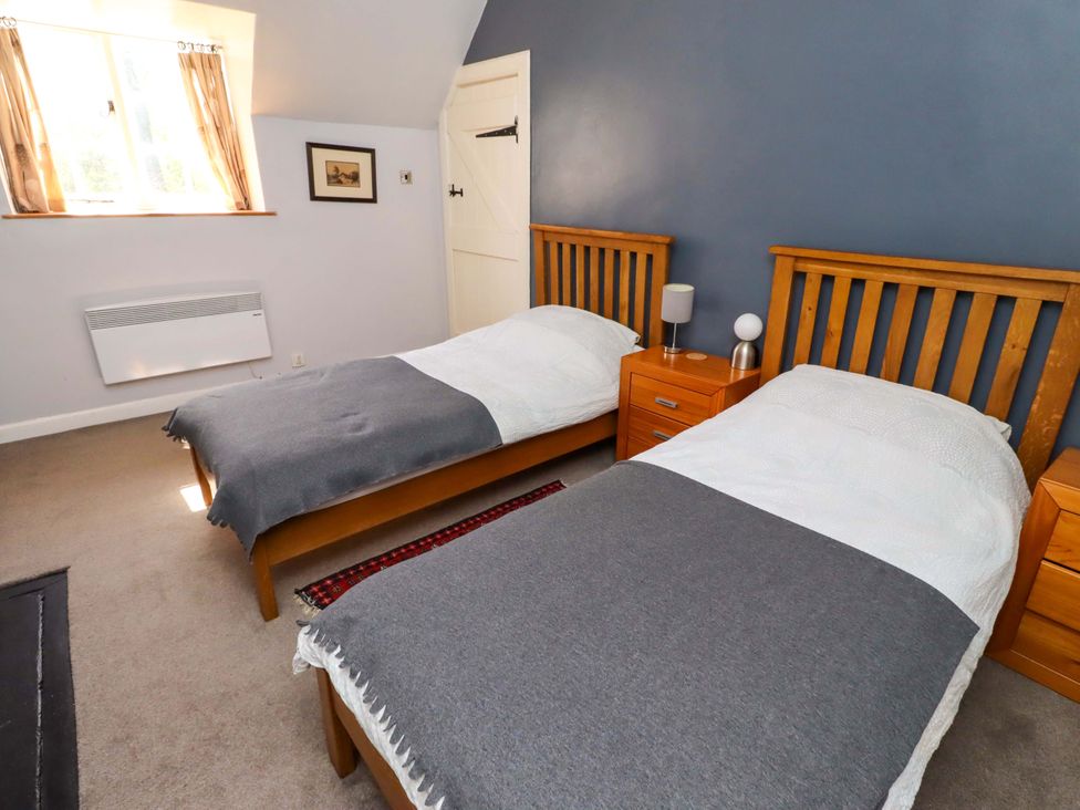 A bedroom with two beds and a window at Gamekeepers Cottage in Chillingham near Chatton