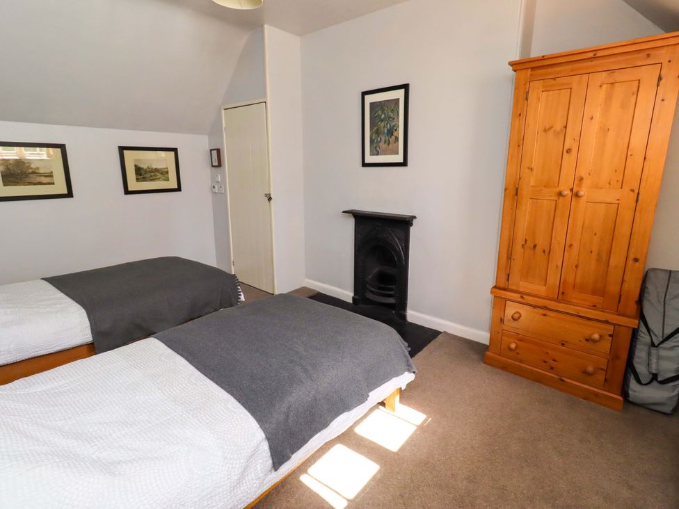 A bedroom with two beds and a wardrobe at Gamekeepers Cottage Chillingham near Chatton