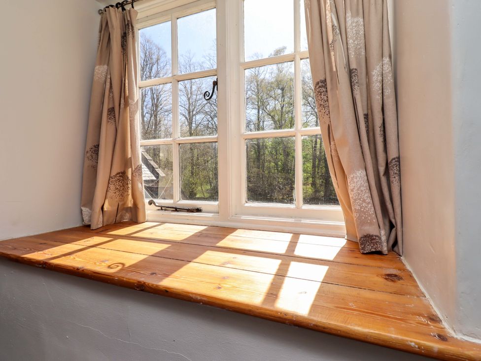 A window with curtains and a wooden sill at Gamekeepers Cottage in Chillingham near Chatton