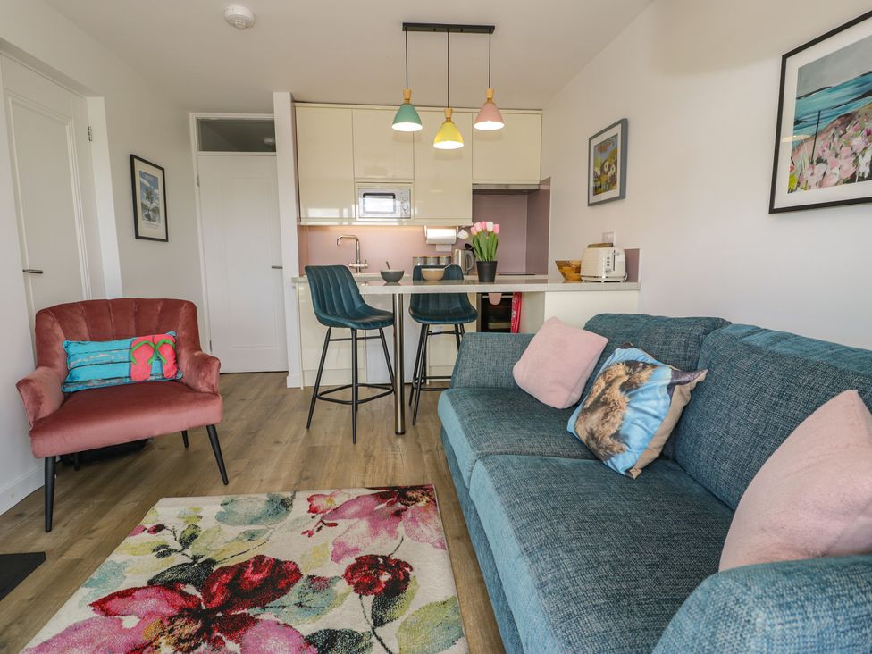 A living room with a couch and kitchen area at Lan y Mor in Porthmadog