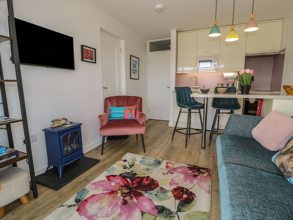 A living room with an armchair and kitchen counter at Lan y Mor in Porthmadog