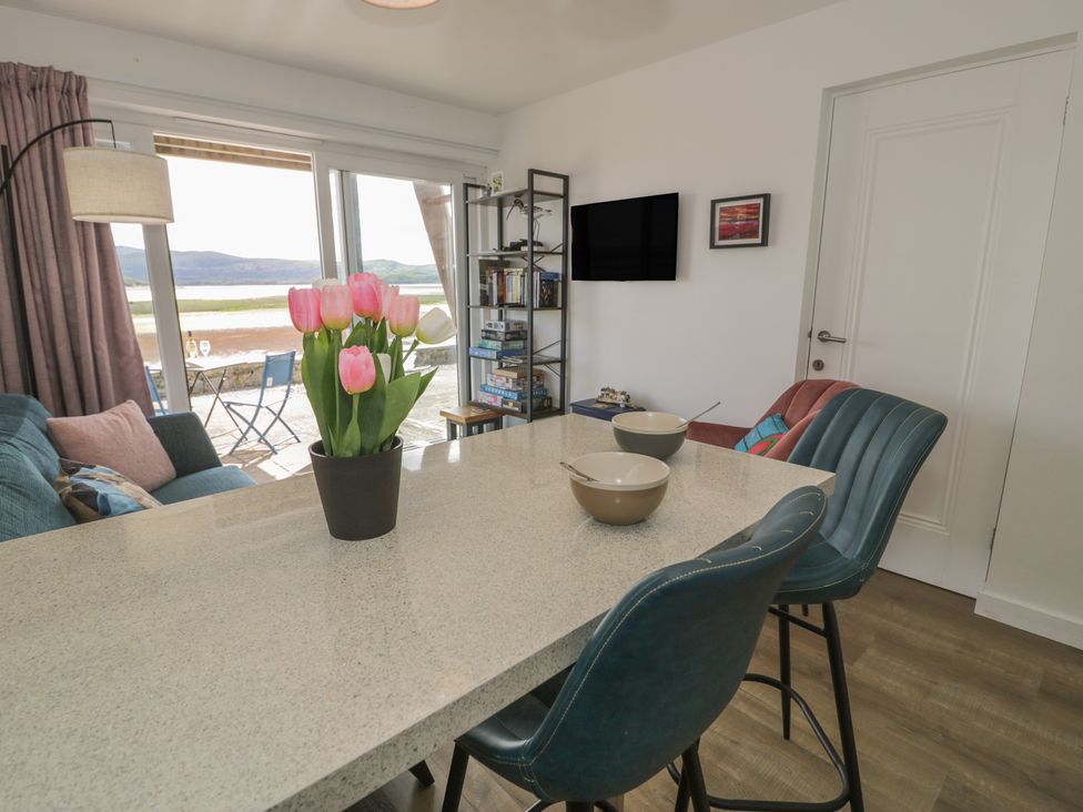 A living room with a sofa, table and chairs at Lan y Mor in Porthmadog