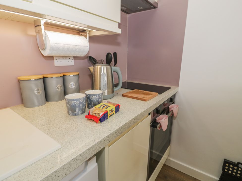 A kitchen with utensils and mugs on a countertop at Lan y Mor in Porthmadog
