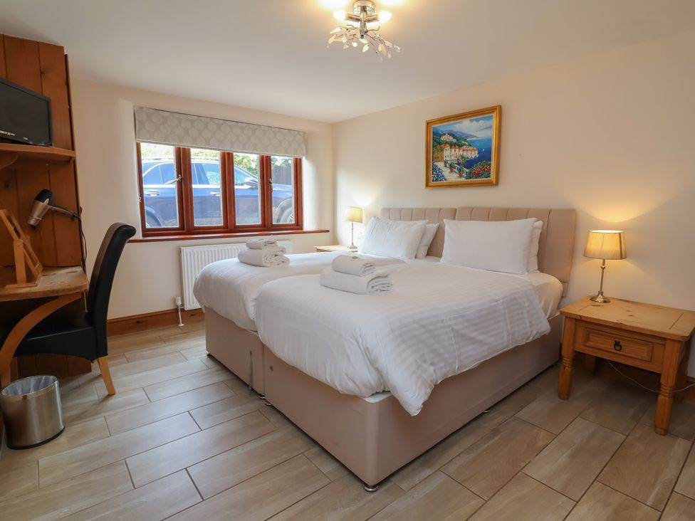 A bedroom with two beds and a desk at The Old Byres in Washford near Watchet