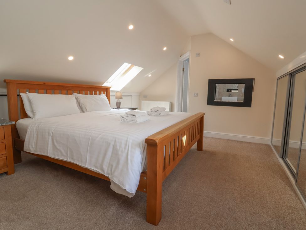 A bedroom with a bed and a mirror at The Old Byres in Washford near Watchet