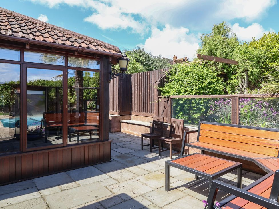 An outdoor patio area with seating and a pool at The Old Byres in Washford near Watchet