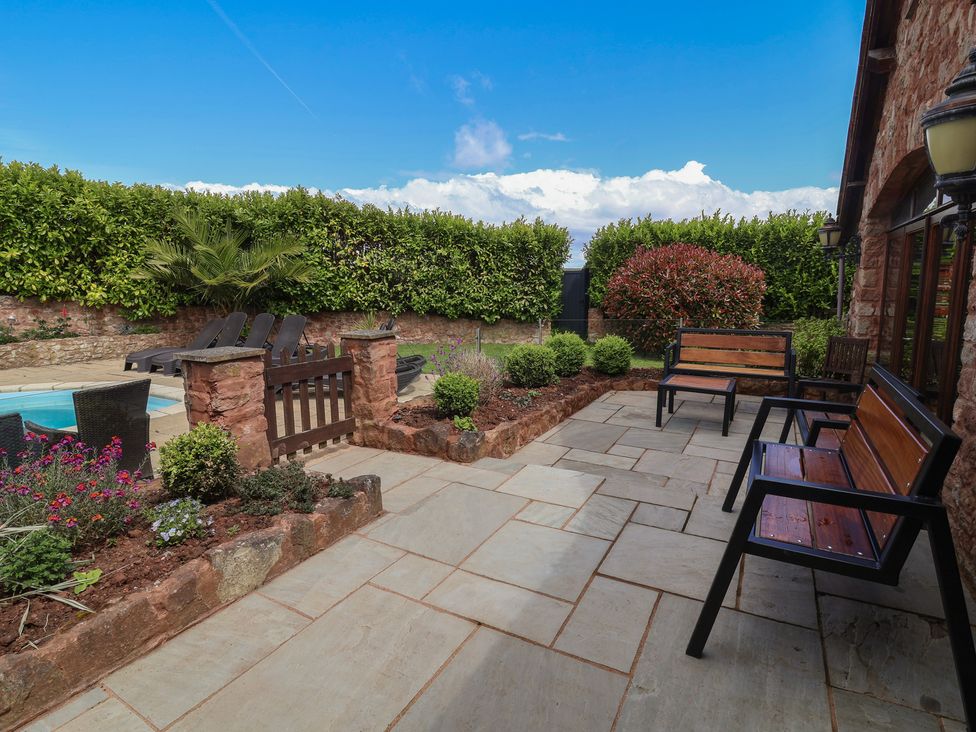 A garden with benches and paved patio at The Old Byres in Washford near Watchet