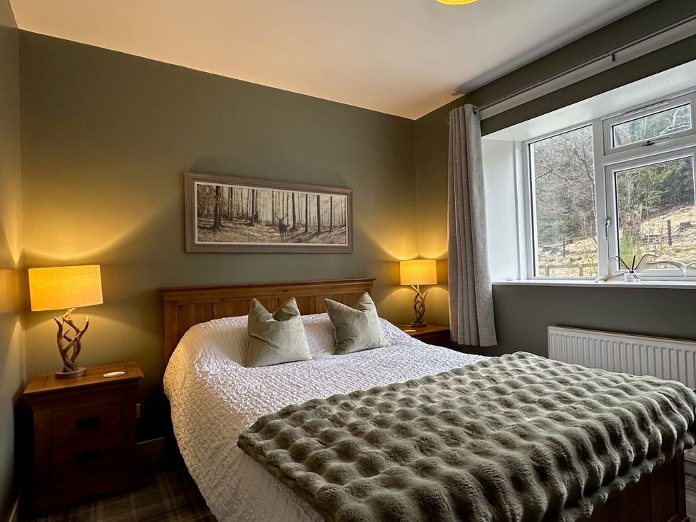 A bedroom with a bed and lamps in White Hillocks Cottage Kirriemuir