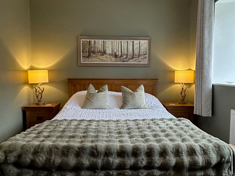 A bedroom with a bed and bedside tables at White Hillocks Cottage in Kirriemuir