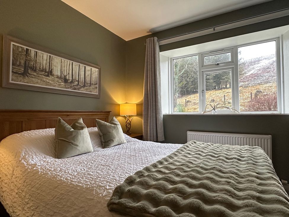 A bedroom with a bed and a window at White Hillocks Cottage Kirriemuir