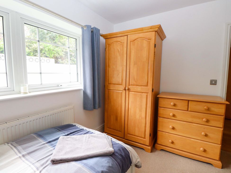 A bedroom with a wardrobe, chest of drawers, and towel at The Bungalow in Morfa Nefyn near Pwllheli