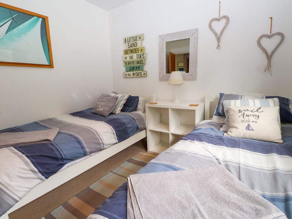 A bedroom with two single beds and a bedside table at The Bungalow in Morfa Nefyn near Pwllheli