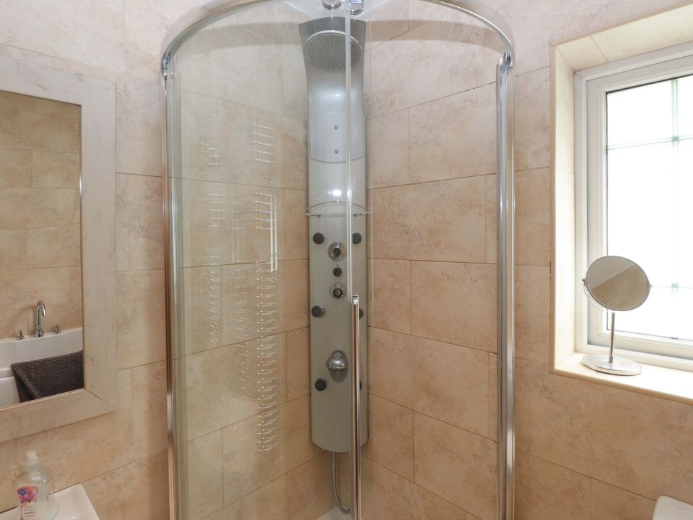 A shower enclosure with controls and a mirror in a bathroom at The Bungalow in Morfa Nefyn near Pwllheli