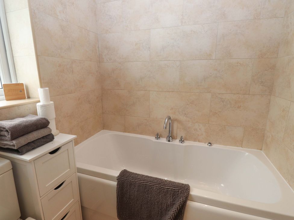 A bathroom with a bathtub and towels at The Bungalow in Morfa Nefyn near Pwllheli