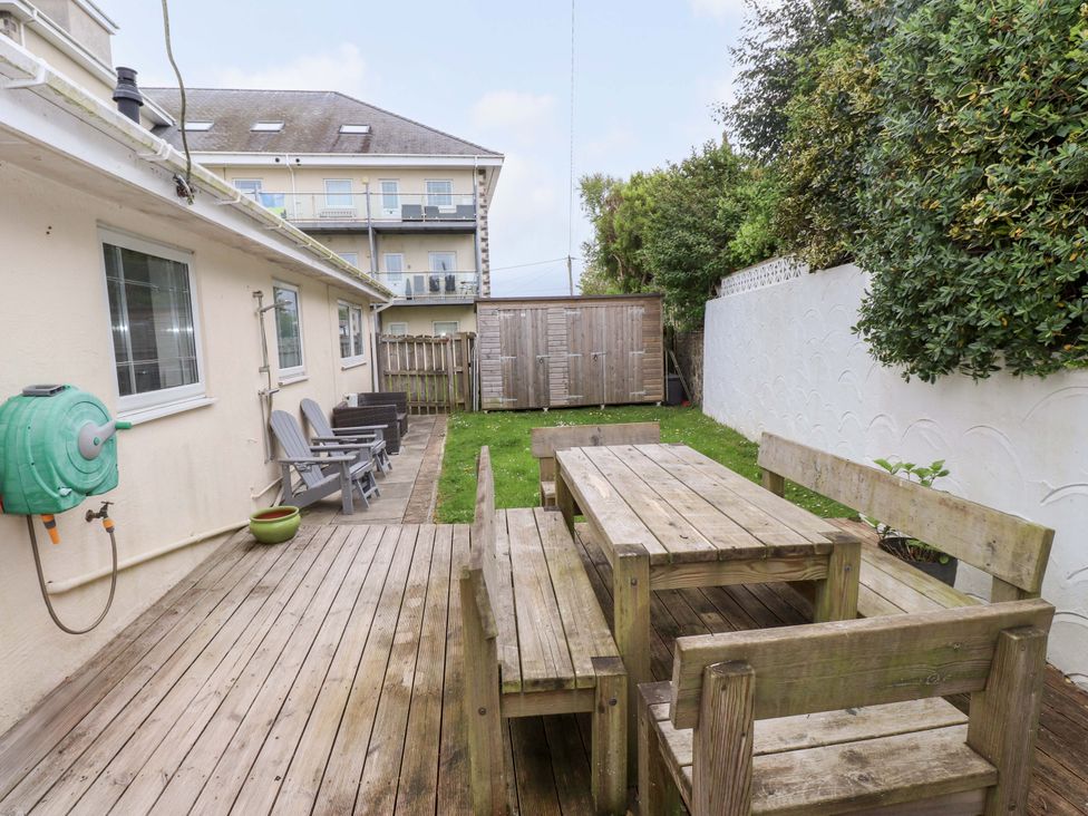 A garden with a wooden deck and furniture at The Bungalow in Morfa Nefyn near Pwllheli