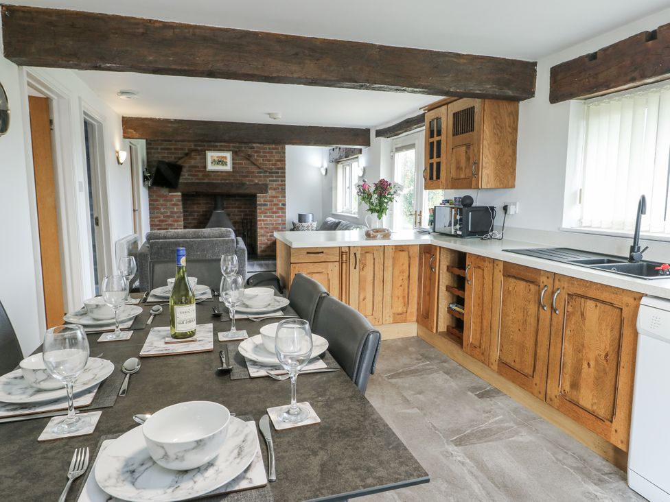 A kitchen with a dining table and chairs at Rhosydd Cottage Benllech