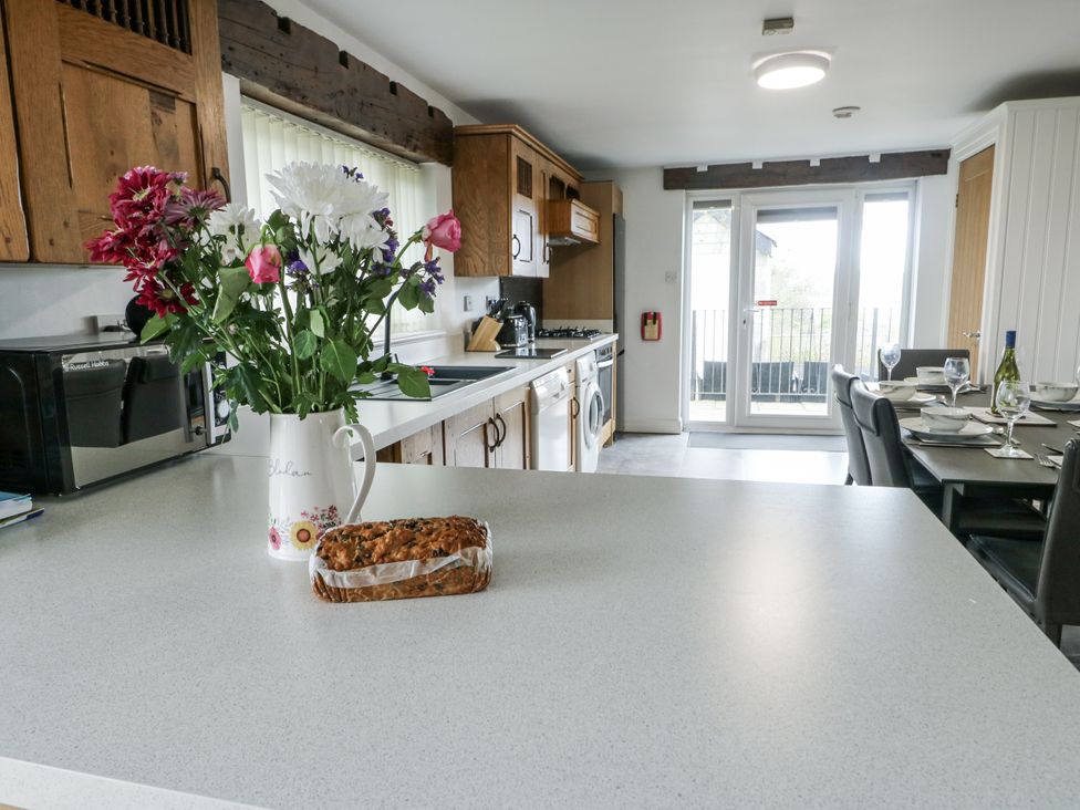 A kitchen with flowers on the counter and a dining table at Rhosydd Cottage in Benllech