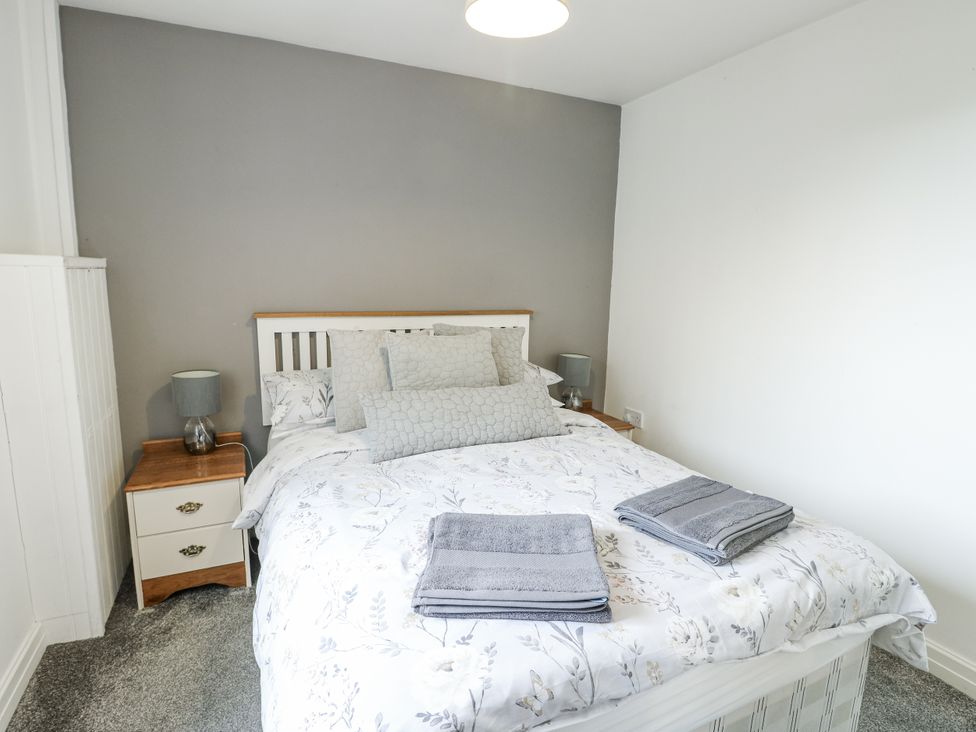 A bedroom with a bed and bedside table at Rhosydd Cottage Benllech