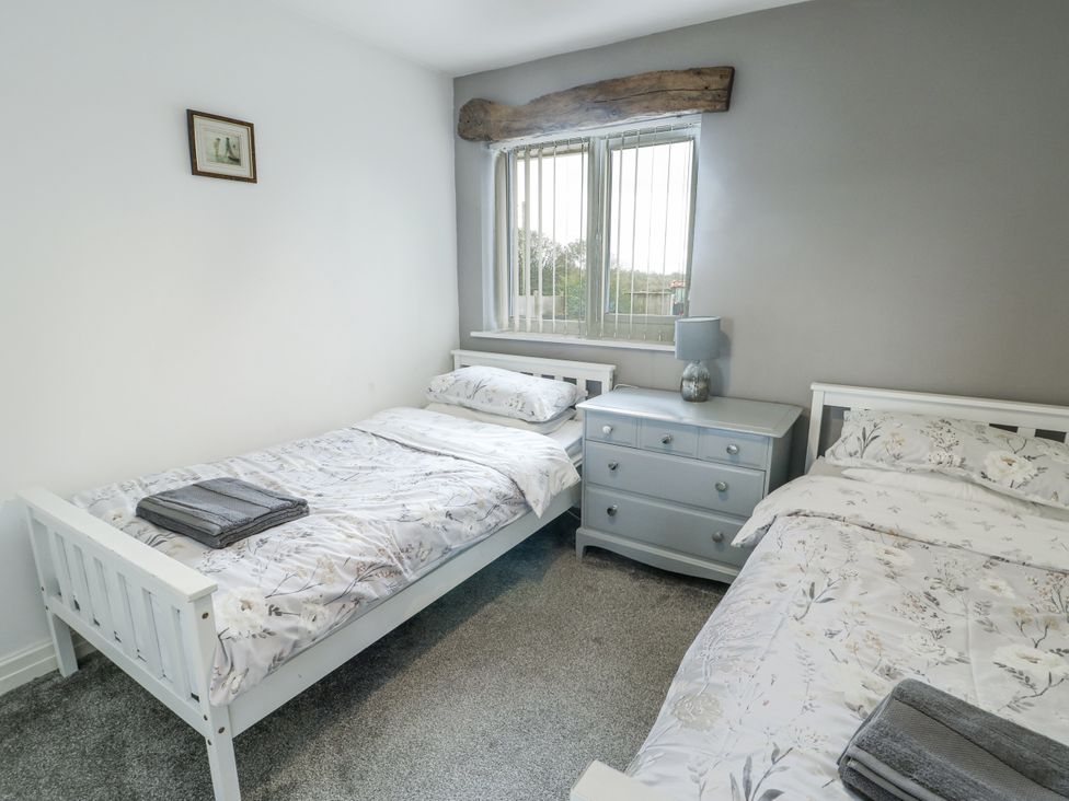 A bedroom with two beds and a dresser at Rhosydd Cottage in Benllech