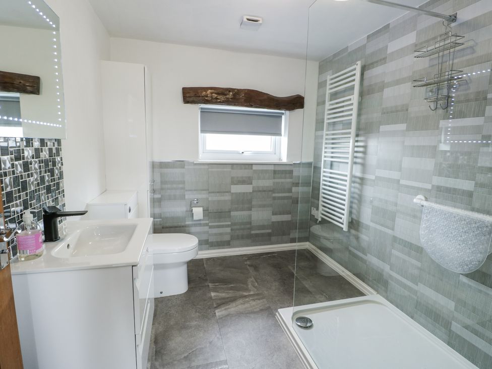 A bathroom with a wash basin and a shower at Rhosydd Cottage Benllech