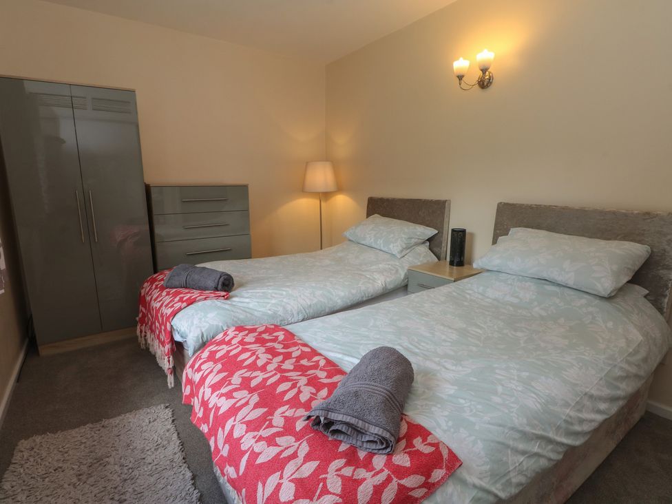 A bedroom with two beds and a wardrobe at West End House in Thornton, West Yorkshire