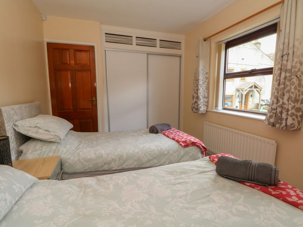 A bedroom with two single beds and a window at West End House Thornton, West Yorkshire