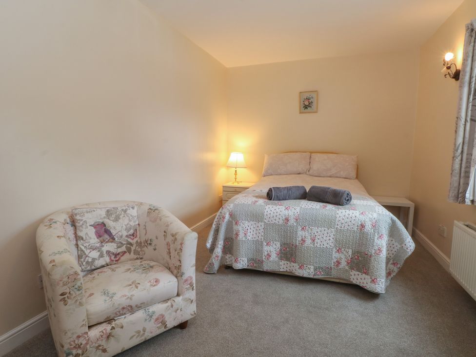 A bedroom with a bed and armchair at West End House Thornton, West Yorkshire