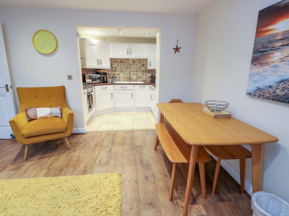A dining room with a table and chairs at Y Enciliad Rhosneigr
