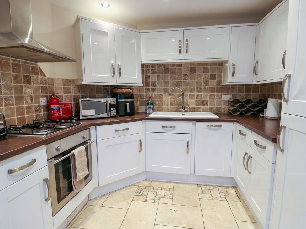 A kitchen with cabinets, oven, sink and countertop at Y Enciliad Rhosneigr