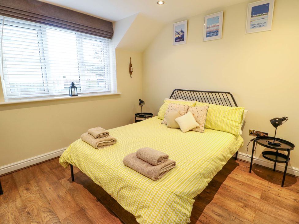 A bedroom with a bed and window at Y Enciliad Rhosneigr