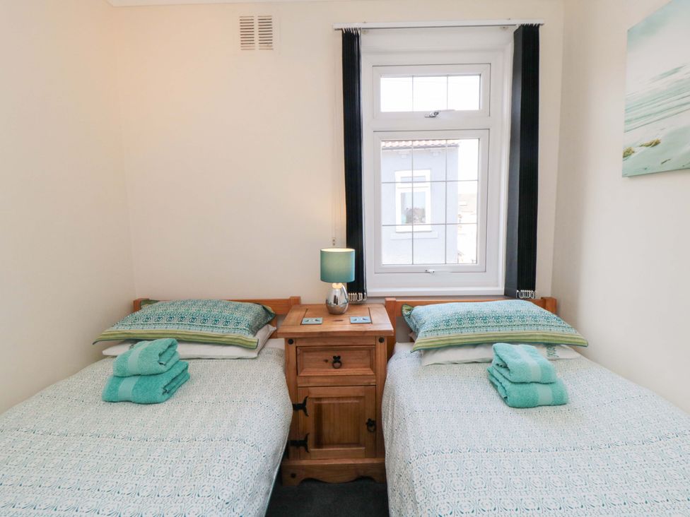 A bedroom with two beds and a window at Sands End Cottage in Marske-by-the-Sea