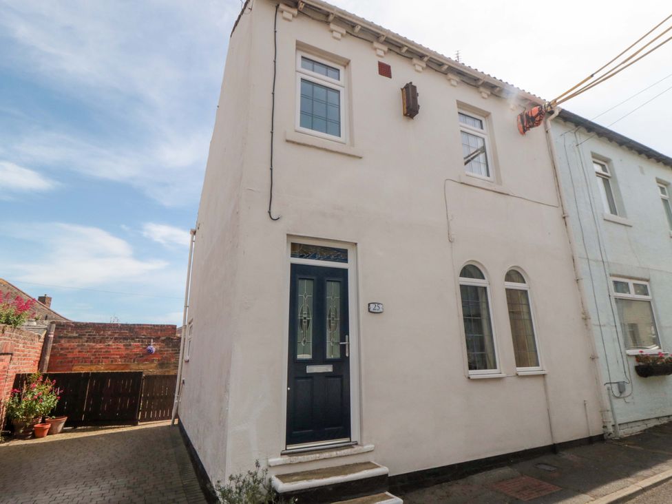 An exterior view of a house with a blue door at Sands End Cottage in Marske-by-the-Sea