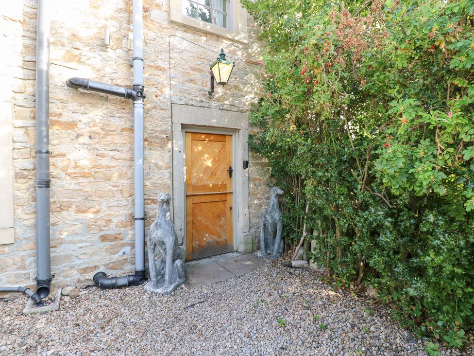 An entrance with a wooden door and stone wall at 2 The Coach House in Romaldkirk near Middleton-in-Teesdale