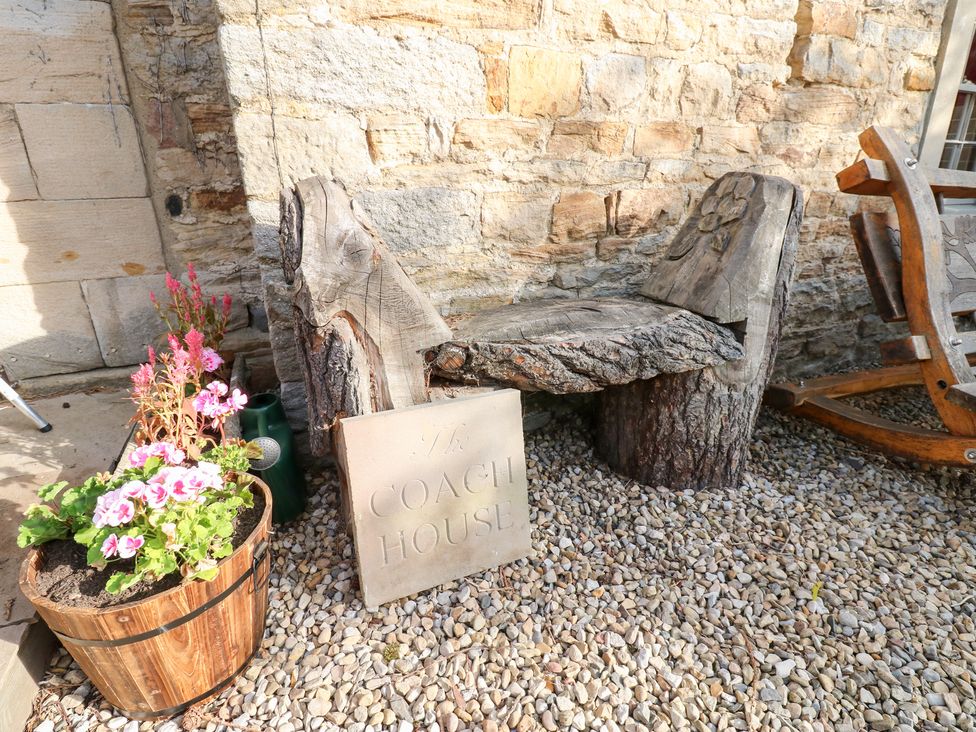 An outdoor area with a wooden bench and flower pot at 2 The Coach House in Romaldkirk near Middleton-in-Teesdale
