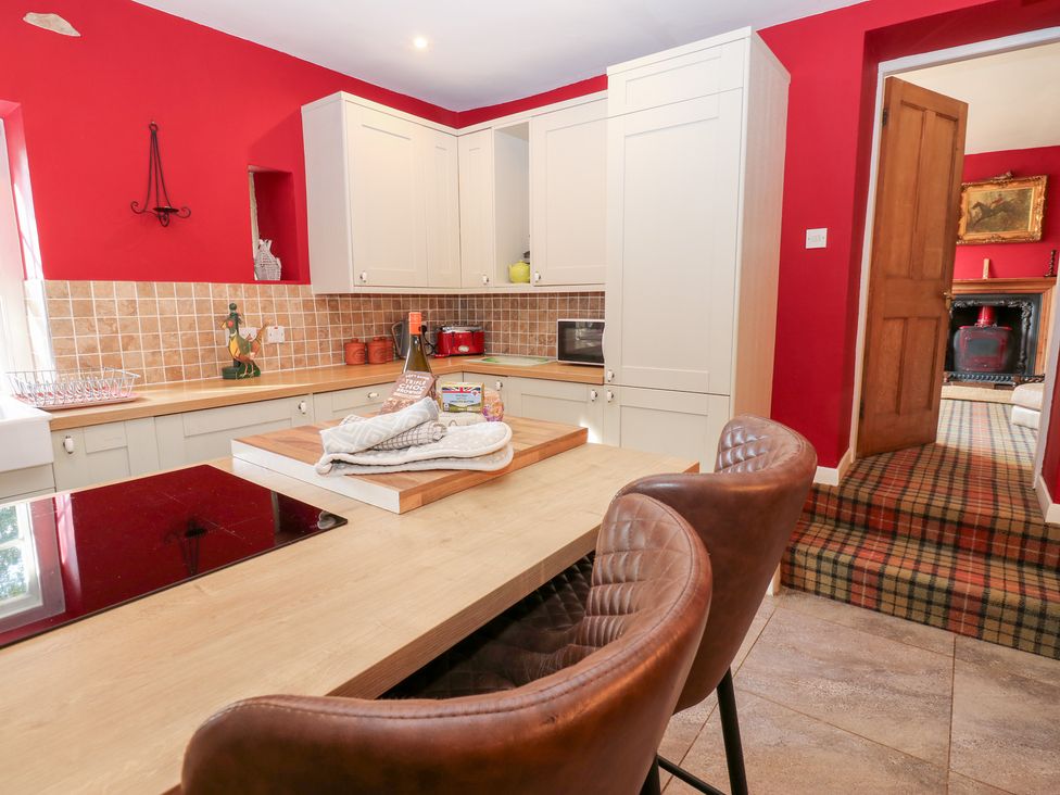 A kitchen with a wooden island and bar stools at 2 The Coach House in Romaldkirk near Middleton-in-Teesdale