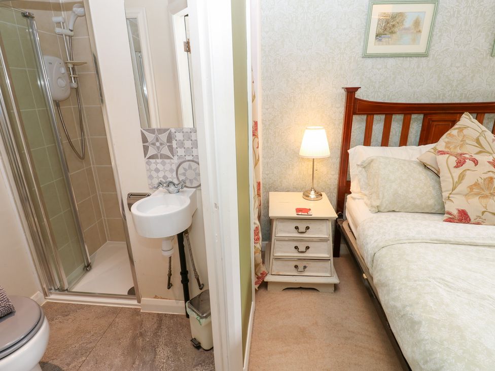 A bathroom with a sink and shower adjacent to a bedroom with a bed at 2 The Coach House Romaldkirk near Middleton-in-Teesdale