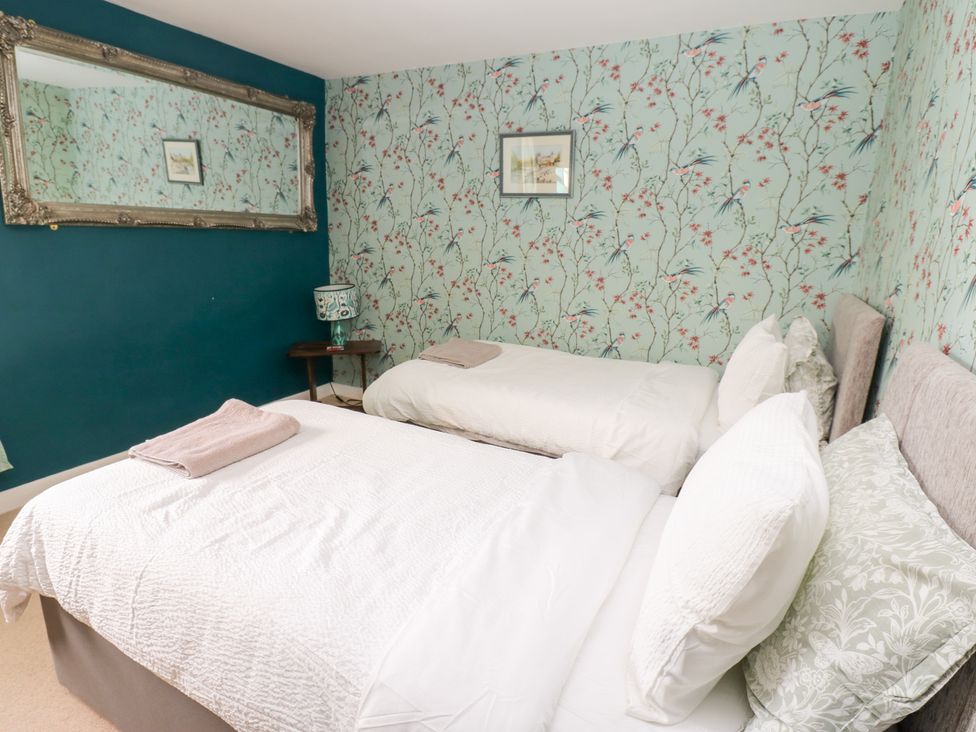 A bedroom with two beds and a mirror at 2 The Coach House Romaldkirk near Middleton-in-Teesdale