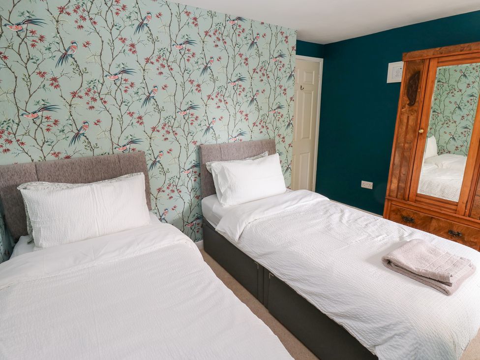 A bedroom with two beds and a wardrobe at 2 The Coach House in Romaldkirk near Middleton-in-Teesdale