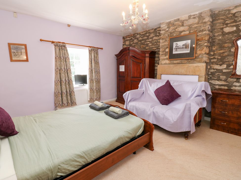 A bedroom with a bed and a wardrobe at 2 The Coach House Romaldkirk near Middleton-in-Teesdale