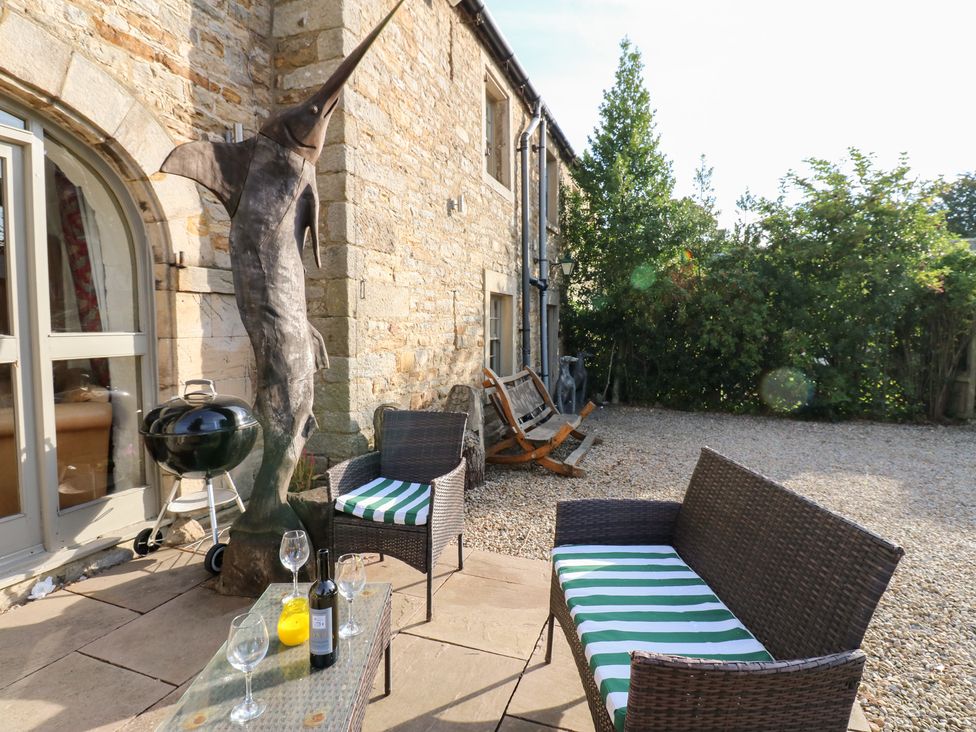 An outdoor seating area with a fishing trophy and barbecue grill at 2 The Coach House Romaldkirk near Middleton-in-Teesdale