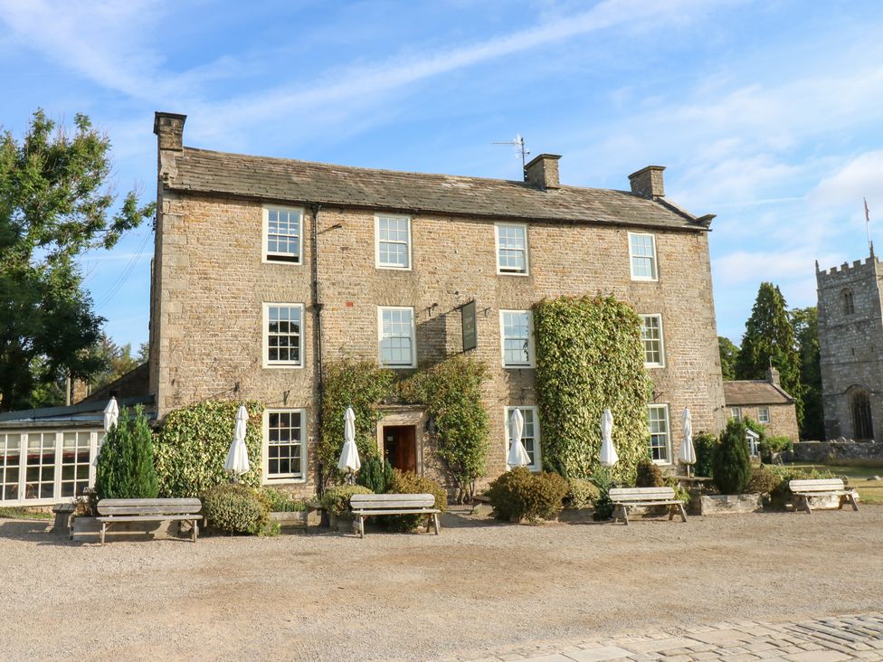 A building with benches and trees in an outdoor space at 2 The Coach House Romaldkirk near Middleton-in-Teesdale